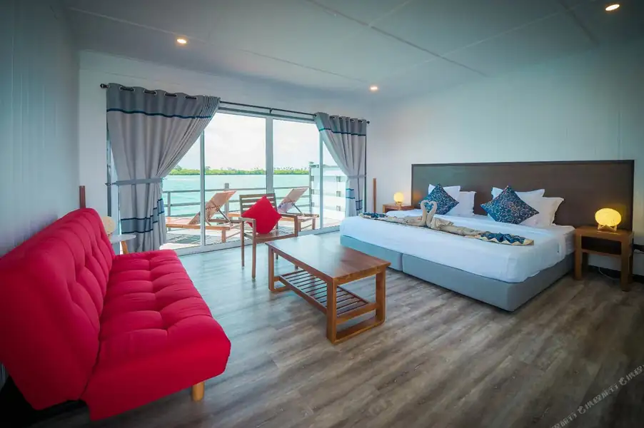 An expansive bedroom at WB Shun Shun Water Bungalows with vibrant lounge seating and ocean view